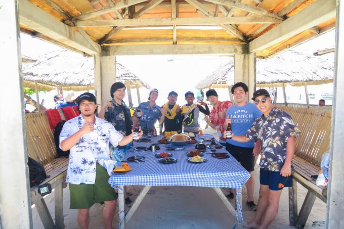 韓流ホッピングでランチを小屋の中で食べる男性5人とスタッフ