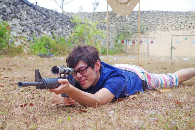 実弾射撃場で寝そべってスナイパーライフルを構える男性